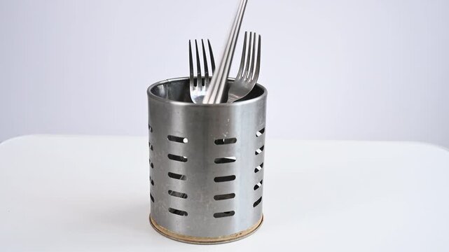 A man stacks cutlery on an iron stand. 