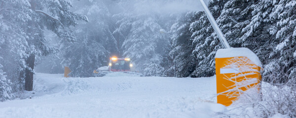 Snow groomer snowcat ratrack machine preparing ski road slope for alpine skiing, winter resort Bansko, Bulgaria