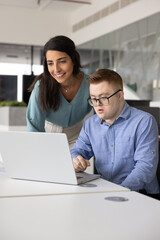 Hispanic mentor checking work result of employee with Down syndrome