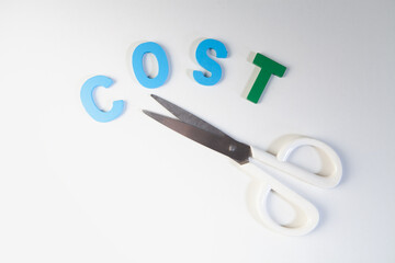Scissors cut the word cost with green and blue letters on white background