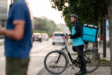 Fototapeta premium Delivery man delivering food with bicycle in the city waiting for the customer