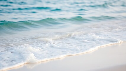 Fototapeta premium Calm blue ocean waves gently rolling onto a white sandy beach, evoking tropical serenity.