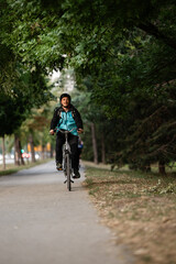 Courier riding bicycle in city park delivering food order