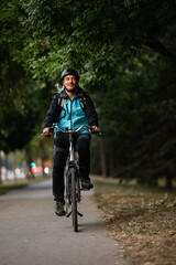 Fototapeta premium Smiling delivery man riding bicycle in city park