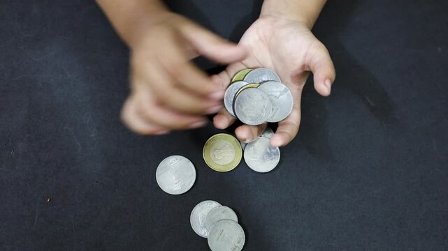 Small hand interacting with Indian coins illustrating growth in money handling skills