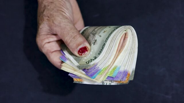 Wrinkled senior hand holding Indian rupee notes symbolizing retirement savings and security