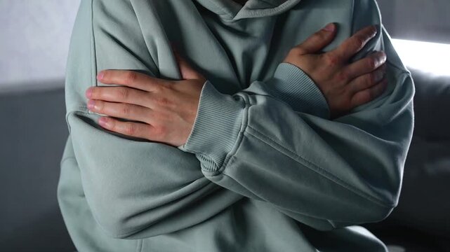 A man in a warm sweater warms himself with his hands from the cold.
A man is shivering from the cold.
Winter and cold.