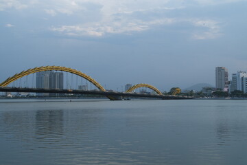 Scenic view of the iconic Dragon Bridge in Da Nang Vietnam spanning the Han River with steel dragon design illuminated by LED lights under sky reflection symbolizing urban growth and cultural identity