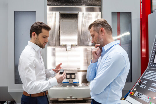 Engineer and colleague discussing component in production facility