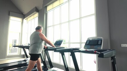 Man exercising on a treadmill in a bright modern gym, sunlight streaming through large windows, focusing on cardio workout and fitness routine. - Powered by Adobe