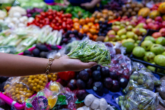 Close-up of a female hand holding a bag of loroco flowers at a local market.