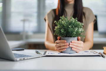 Businesswoman holding green plant promoting environmental sustainability at work