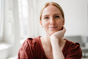Smiling woman with freckles posing in loft with natural daylight