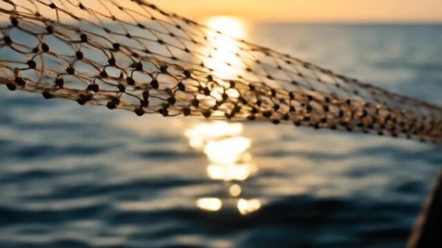 Fishing net detail with sunlight over sea water at sunset horizon