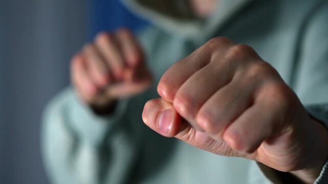 A man in a blue sweater is fighting with clenched fists.
Abiere is waving his fist and provoking a conflict.
Domestic violence