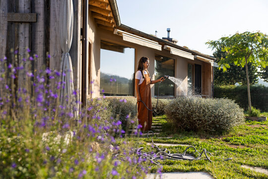 Woman watering xerophytic plants in eco garden at sustainable home