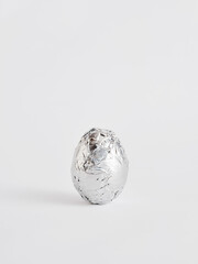 Silver foil wrapped egg on white background