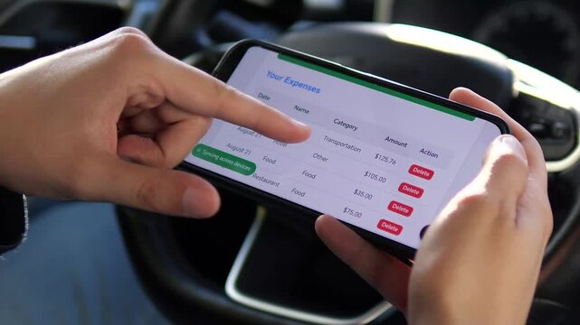A man's hands in a parked car carefully review daily spending entries in a financial tracking application on his smartphone. His finger scrolls through the list of expenses, analyzing the data. 