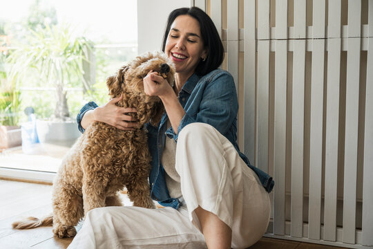 Playful woman sitting with dog at home