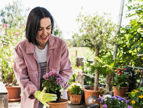 Happy woman wearing glove and doing gardening in back yard
