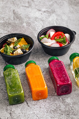 Top view on healthy salads and smoothies in black delivery containers