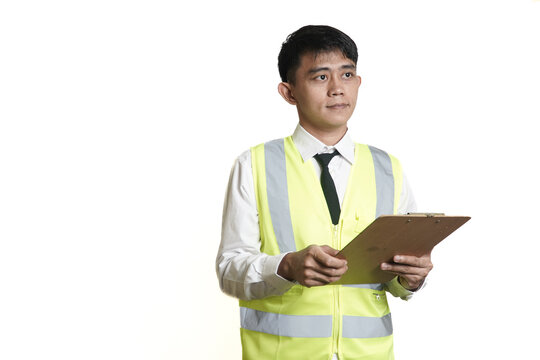Professional male supervisor in a high-visibility vest meticulously checking a list on his clipboard during a workplace inspection