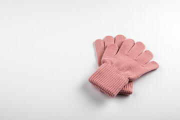 A pair of soft pink wool gloves placed on a white background. Warmth, comfort and protection during the cold season