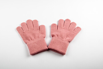 A pair of pink knitted wool gloves on a white background. Warmth, comfort and cozy winter clothing essentials