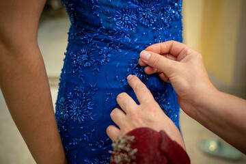 Woman's hand sewing a blue evening dress