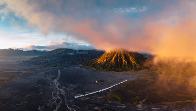 Aerial view of the Bromo Tengger Semeru National Park, where the sun kisses the volcanic peaks amid swirling clouds, creating a dramatic landscape, Mt. Bromo, East Java, Indonesia.