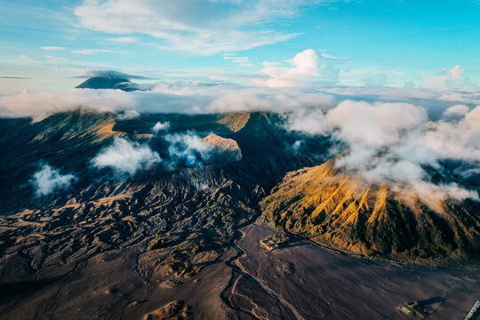 Aerial view of the rugged, volcanic landscape of Mt. Bromo, with its sharp peaks piercing through the soft, enveloping clouds, Mt. Bromo, East Java, Indonesia.