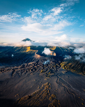 Aerial view of a dramatic volcanic landscape with swirling clouds and textured terrain, a symphony of light and shadow, Mt. Bromo, East Java, Indonesia.