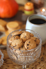 Lit candles, cookies, chocolate, nuts, tea, wine, pumpkins, books, reading glasses and autumn leaves on the table. Autumnal hygge at home. Selective focus.