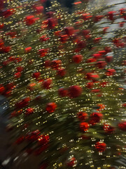 Close-up of a decorated Christmas tree with sparkling ornaments and warm lights, motion blur