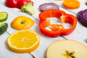 sliced fruit and vegetable circles on white wood table