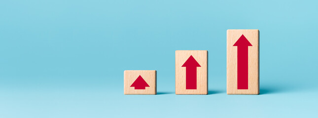 Wooden cube with red arrow up on blue background, Ladder of success in business growth concept, copy space