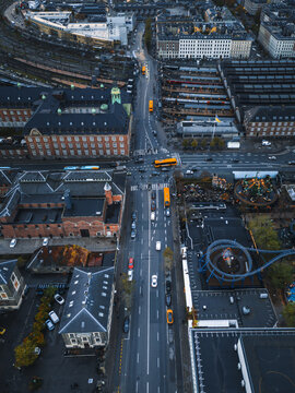 Aerial view of grey streets cutting through red brick buildings, contrasting with the blue rollercoaster, Copenhagen, Denmark.