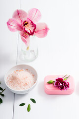 cosmetic cream, soap and bath salt with pink flower, white wood table