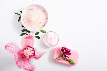 cosmetic cream, soap and bath salt with pink flower, white wood table