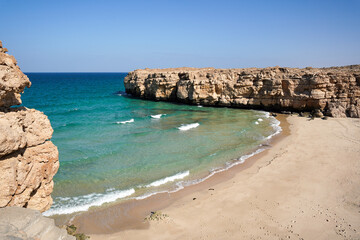 Beautiful hidden wild beach in Oman with turquoise water and yellow sand