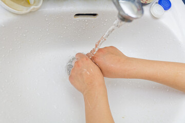 Child Washing Hands Under Running Water in Bathroom Sink for Hygiene and Cleanliness