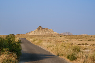 Fototapeta premium Road Through Bardenas Reales Desert Landscape, Navarra Spain, Eroded Hills and Badlands, Semi-Arid Terrain, Natural Park