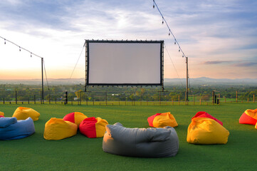 open air cinema with colorful bean bag. empty white screen, free space for text or montage.