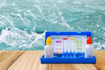 Water tester test kit on wooden table over clear water background, quality water testing test kit, pool maintenance and service business concept