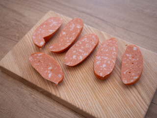 Sliced traditional Czech and Slovak sausages with visible fat pieces on wooden cutting board, close up of spekacky texture, ready for cooking or grilling.