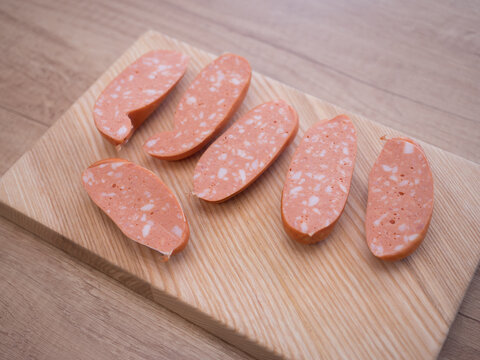 Sliced traditional Czech and Slovak sausages with visible fat pieces on wooden cutting board, close up of spekacky texture, ready for cooking or grilling.