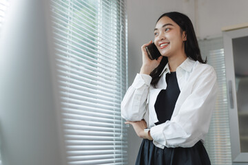 Smiling young asian woman talking on cell phone