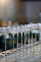 Row of empty cocktail glasses filled with ice on bar counter in focus.