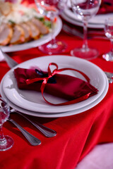 Festive table setting with white plates and a burgundy napkin