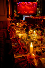 Close-up of a long table with flowers and burning candles in a dark room